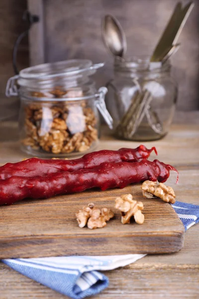 Sabrosos dulces orientales (churchkhela) y nueces frescas, sobre fondo de madera — Foto de Stock