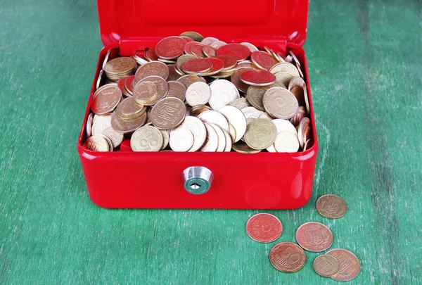 Rectangular red open suitcase with Ukrainian coins on wooden table — Stock Photo, Image