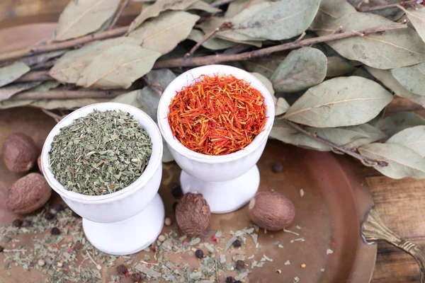 Small round tea bowls with different seasoning and bay leaves on a metal round tray on wooden background — Stock Photo, Image