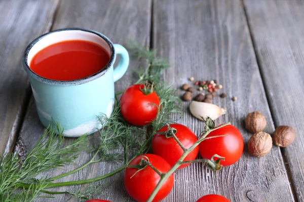 Sumo de tomate caseiro na caneca a cores, especiarias e tomates frescos no fundo de madeira — Fotografia de Stock