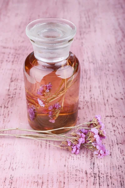 Butelka nalewki i szkła ziół na różowym tle drewniane — Zdjęcie stockowe