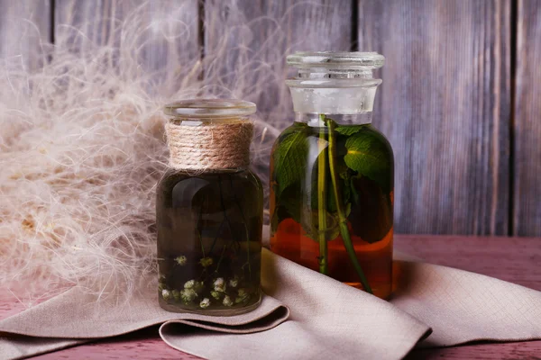 Bottles of herbal tincture on a napkin on  wooden table in front of wooden wall — Stock Photo, Image