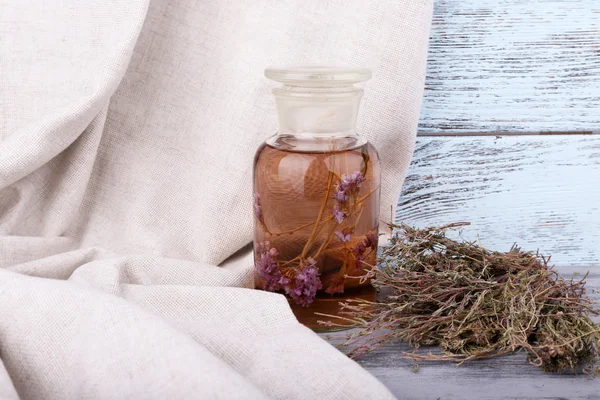 Bottles of herbal tincture and dried herbs on a napkin on wooden background in front of curtain — Stock Photo, Image