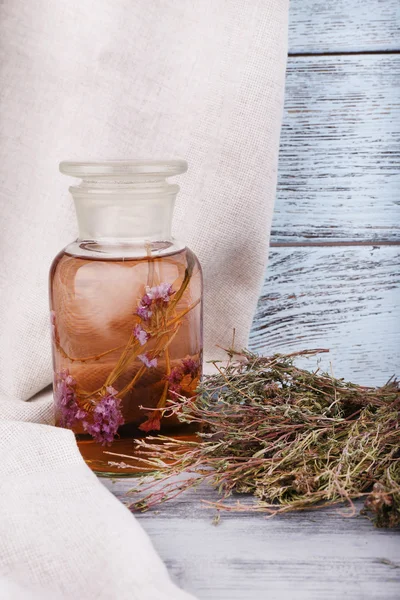 Μπουκάλια φυτικό βάμμα και αποξηραμένα βότανα σε μια χαρτοπετσέτα σε ξύλινα φόντο μπροστά από την κουρτίνα — Φωτογραφία Αρχείου