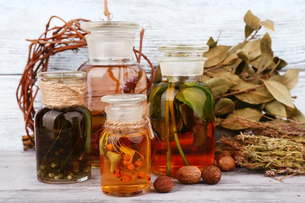 Bottles of herbal tincture and dried leaves on wooden background — Stock Photo, Image