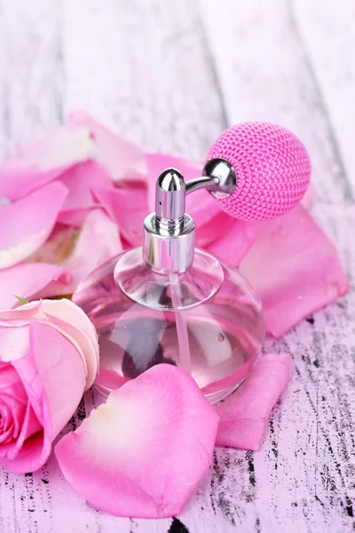 Perfume bottle with roses petals on table close-up — Stock Photo, Image