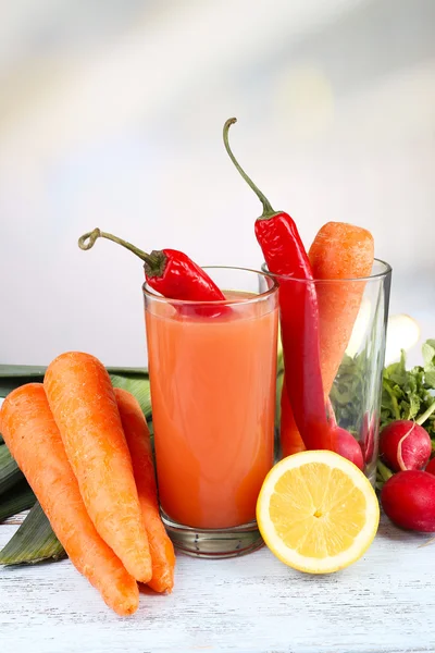 Glas färsk morotsjuice med grönsaker på träbord — Stockfoto