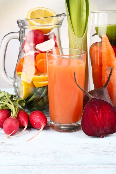 Słoik cięcia warzyw i szklankę świeżego soku z marchwi z warzywami na drewnianym stole — Zdjęcie stockowe