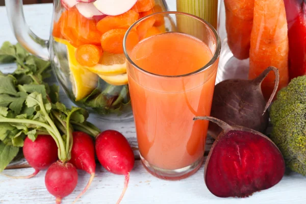 Pot de légumes coupés et verre de jus de carotte frais avec légumes sur table en bois — Photo