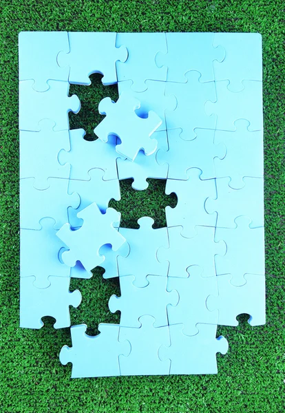 Puzzle de piezas sobre fondo de hierba verde. Concepto de espacio verde — Foto de Stock