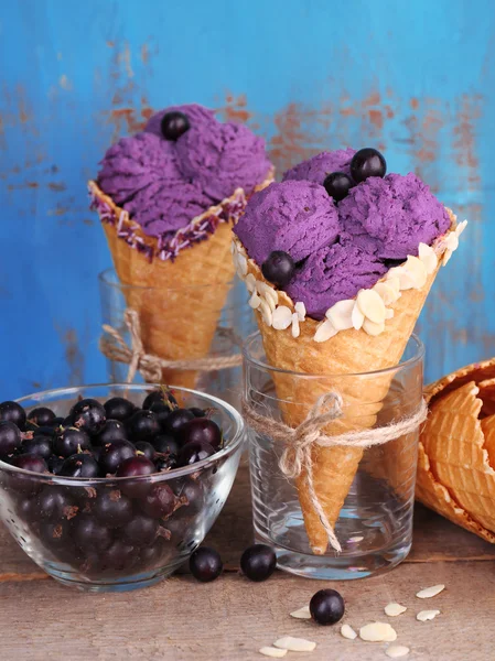 Tasty ice cream with berries in waffle cones on blue wooden background — Stock Photo, Image