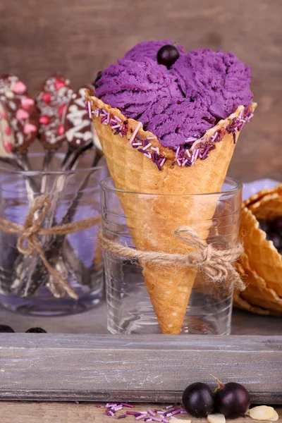 Tasty ice cream with berries in waffle cone on brown wooden background — Stock Photo, Image