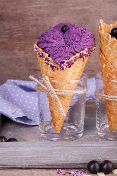 Läckra glass med bär i waffle cone på brunt trä bakgrund — Stockfoto