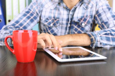 tahta masada oturan ve tablet portre üzerinde çalışan adam