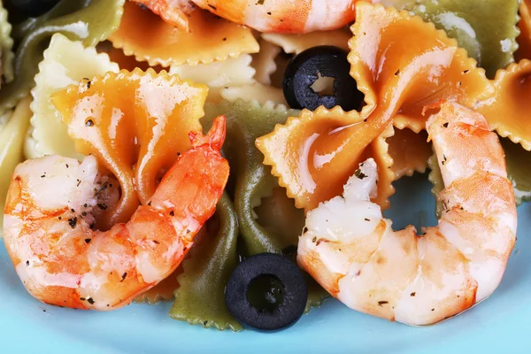 Fresh prawns with coloured macaroni and olives in a blue plate closeup — Stock Photo, Image