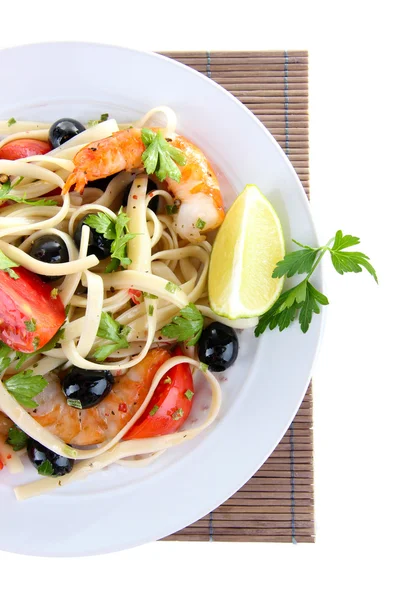 Fresh prawns with spaghetti, olives, tomatoes and parsley in a big round plate on a napkin on white background isolated — Stock Photo, Image