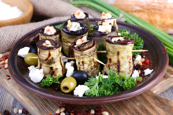 Fried aubergine with cottage cheese in a round plate on wooden cutting board on wooden background — Stock Photo, Image