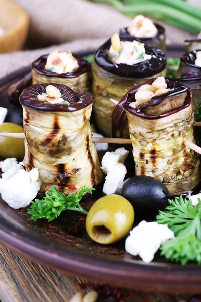 Gebakken aubergine met cottage kaas in een ronde plaat op houten snijplank op houten achtergrond — Stockfoto