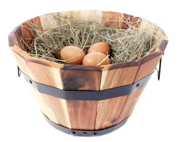 Grande cesto di legno con n erba secca e uova isolate su bianco — Foto Stock