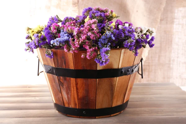 Grande cesta de madeira com flores frescas no fundo de saque — Fotografia de Stock