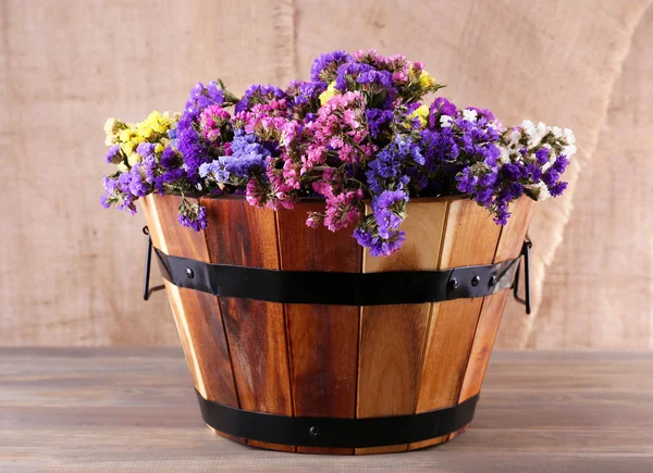 Grand panier en bois avec des fleurs fraîches sur fond de sac — Photo