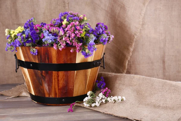 Grande cesta de madeira com flores frescas no fundo de saque — Fotografia de Stock