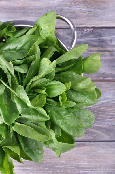 Plukje verse sorrel in metalen vergiet op houten achtergrond — Stockfoto