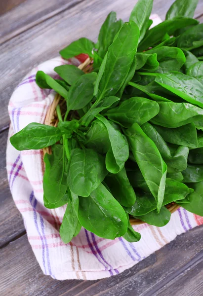 Verse sorrel in ronde rieten mand op servet op houten achtergrond — Stockfoto