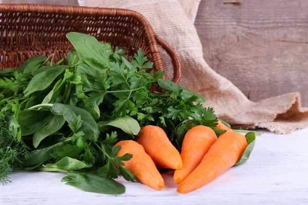 Wortelen, peterselie en zuring in rechthoekige rieten mand op houten achtergrond — Stockfoto