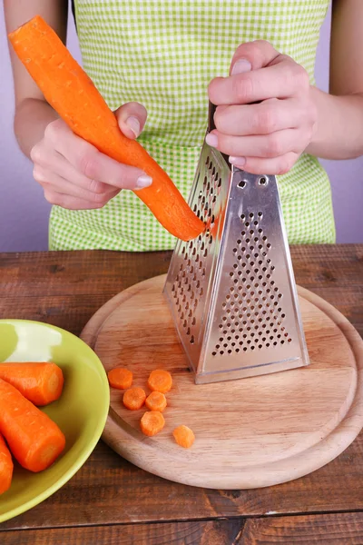 Vrouw raspen wortel in keuken op lichte achtergrond — Stockfoto