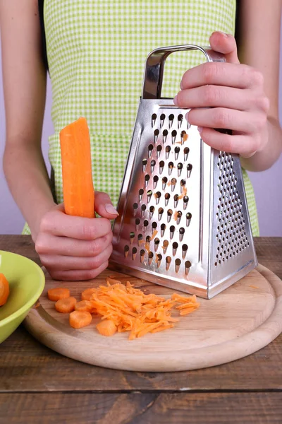Жінка натирає моркву на кухні на світлому фоні — стокове фото