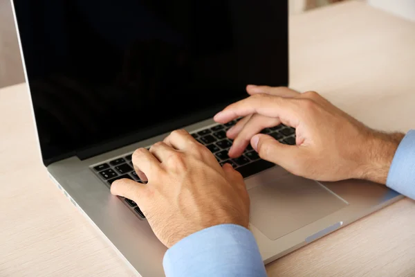 Man aan het werk op laptop op houten tafel op mapachtergrond — Stockfoto