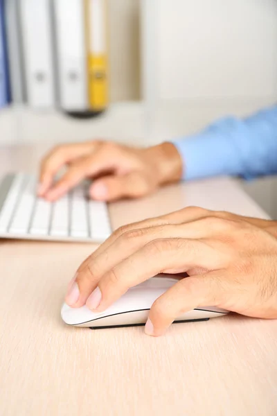 Man aan het werk met toetsenbord op houten tafel op mappen achtergrond close-up — Stockfoto