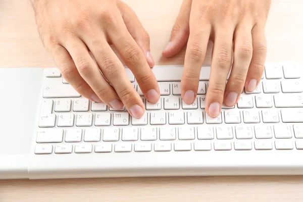 Mann arbeitet mit Tastatur auf Holztisch auf Ordnern Hintergrund Nahaufnahme — Stockfoto
