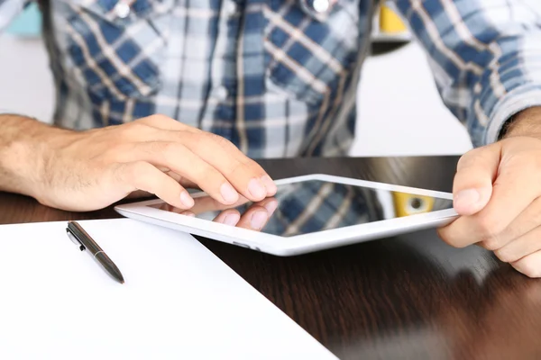 Hombre sentado en la mesa de madera y trabajando en primer plano tableta —  Fotos de Stock