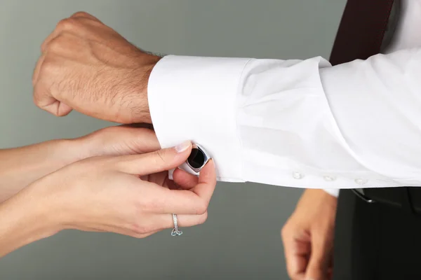 Donna aiutare l'uomo a fare collare pulsante su sfondo grigio — Foto Stock