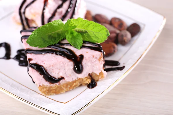 Torta con menta fresca e glassa di cioccolato su piatto su fondo di legno — Foto Stock