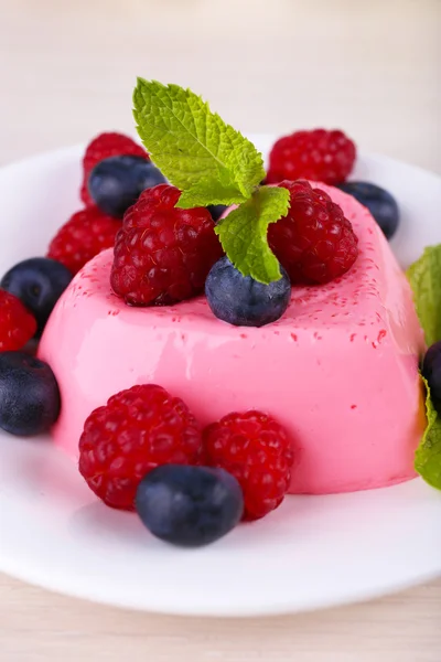 Heart shaped cake with berries on plate on wooden background — Stock Photo, Image