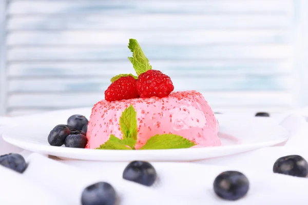 Torta a forma rotonda con bacche su piatto su tovaglia su tavolo su sfondo chiaro — Foto Stock