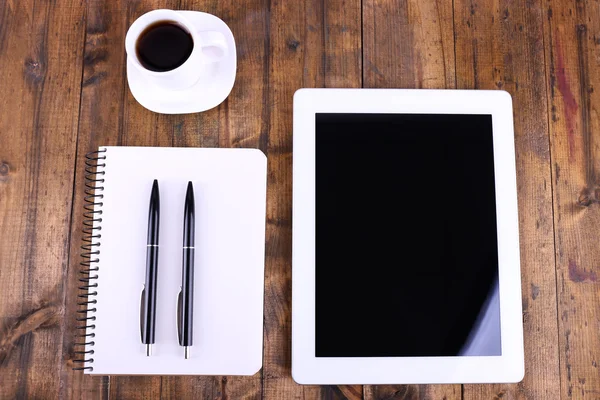 Tablet, cup of coffee, notebook and pens on wooden background — Stock Photo, Image