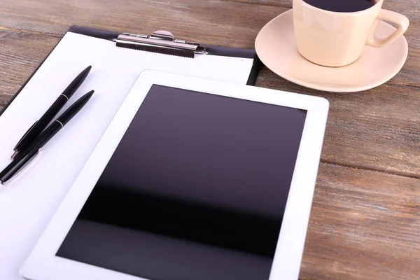 Tablet, cup of coffee, pens and folder with paper on wooden background — Stock Photo, Image