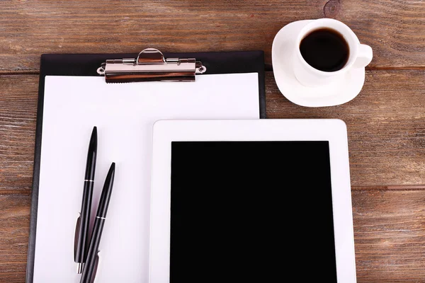 Tablet, cup of coffee, pens and folder with paper on wooden background — Stock Photo, Image