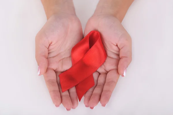 Woman with aids awareness red ribbon in hands isolated on white — Stock Photo, Image
