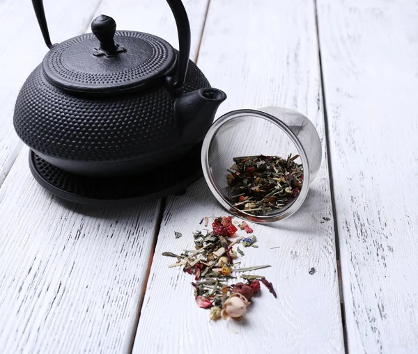 Μαύρο τσαγιέρα, μπολ και τσάι σε ξύλινα φόντο χρώμα — Φωτογραφία Αρχείου