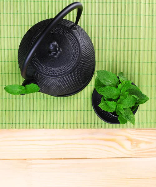 Chinese traditional teapot with fresh mint leaves on wooden background — Stock Photo, Image