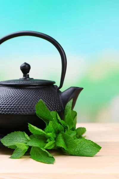 Chinese traditional teapot with fresh mint leaves on wooden table, on bright background — Stock Photo, Image