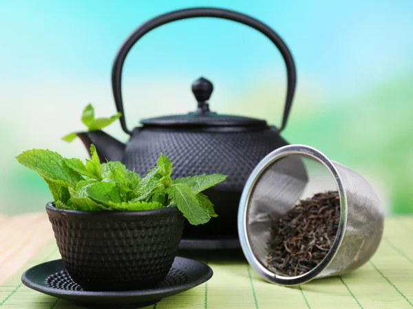 Chinese traditional teapot with fresh mint leaves on wooden table, on bright background — Stock Photo, Image