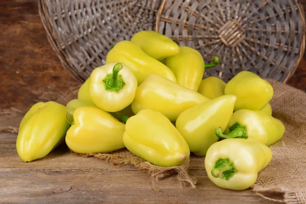 Yellow peppers on sackcloth on wicker background — Stock Photo, Image