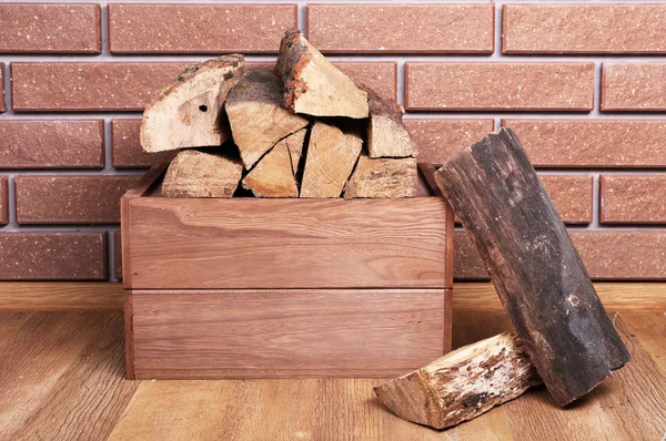 Дерев'яна коробка з дровами на підлозі на цегляному фоні — стокове фото