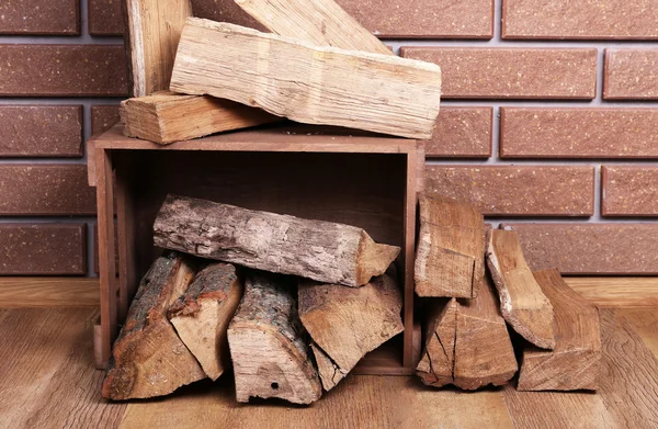 Holzkiste mit Brennholz auf dem Fußboden auf Ziegelgrund — Stockfoto